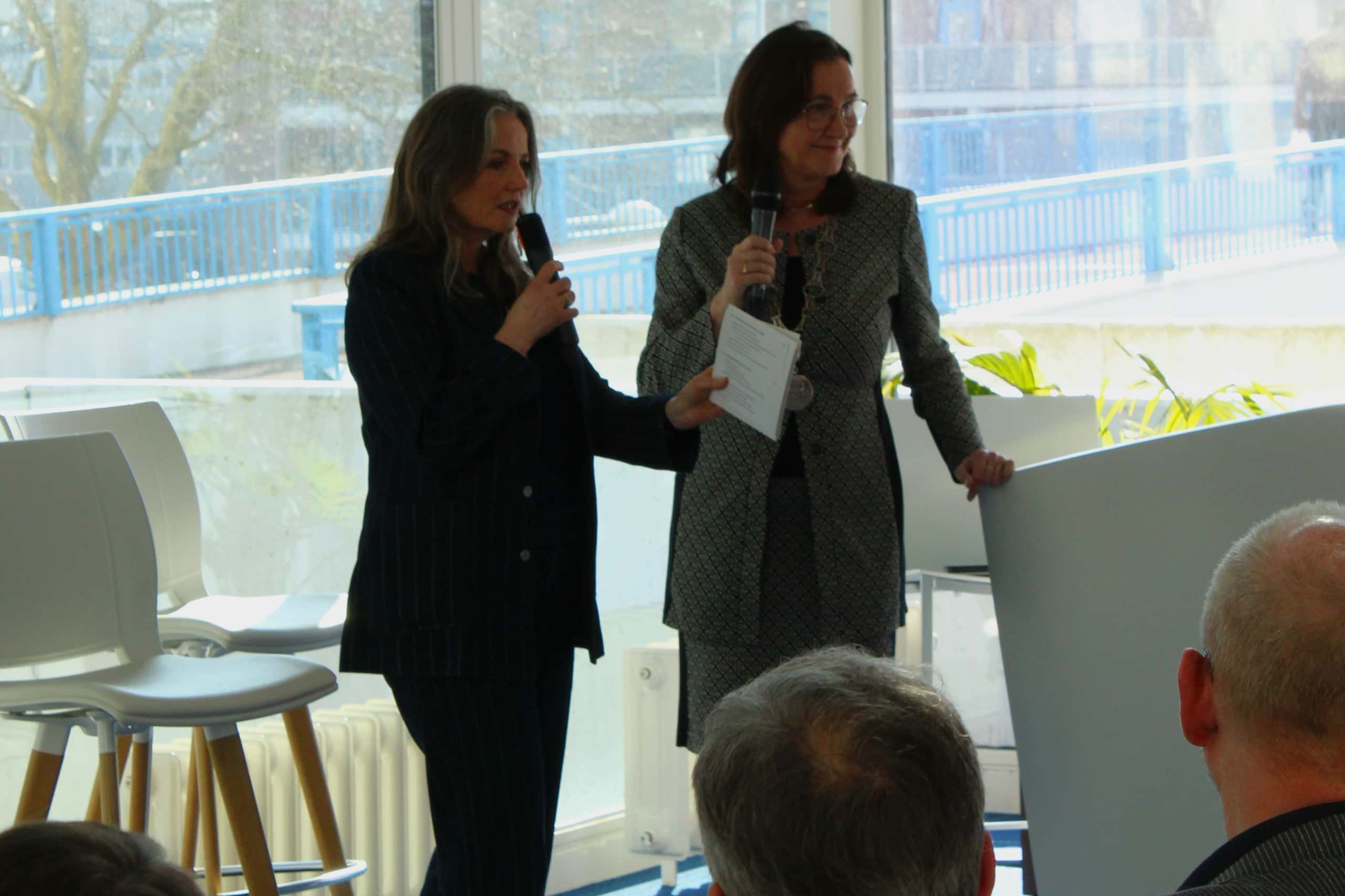 Op deze foto zie je gespreksleider Esther van Rijswijk voor de zaal in gesprek met burgemeester Baltus.